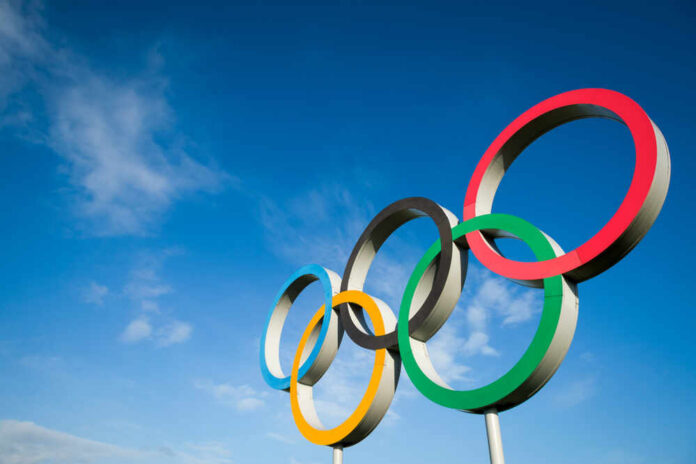 Five colorful Olympic rings against a clear blue sky
