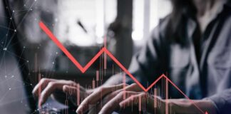 Person typing on a laptop with a declining stock market graph overlay