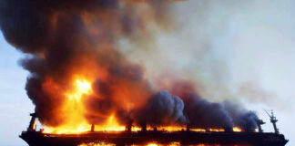 Large ship engulfed in flames on the ocean.