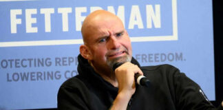 Bald man with goatee holding microphone.