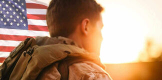 Soldier in uniform with American flag at sunset.