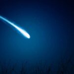 A bright comet streaking across a dark night sky filled with stars