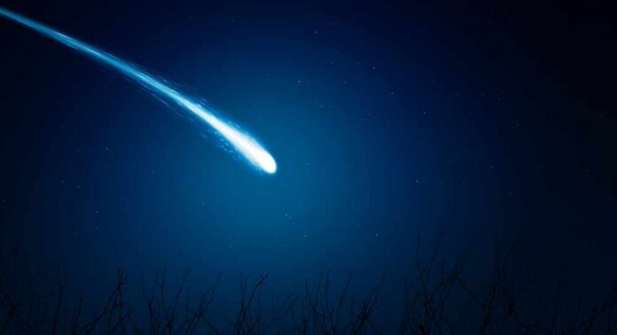 A bright comet streaking across a dark night sky filled with stars