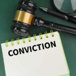 A gavel resting on a notepad with the word 'CONVICTION' written on it