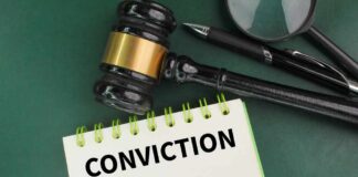 A gavel resting on a notepad with the word 'CONVICTION' written on it