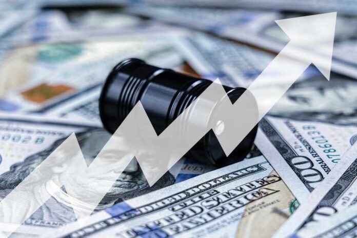 shutterstock_2605409679.jpg An oil barrel placed on a background of dollar bills with an upward trend graph overlay