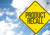 Yellow product recall sign against cloudy sky