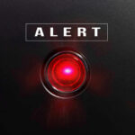Red alert light against black background, text ALERT.