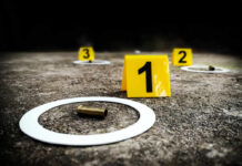 Crime scene with evidence markers and a bullet casing on the ground