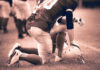 Football player kneeling on the field with a helmet beside them