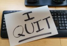 A resignation letter reading 'I QUIT' placed on a keyboard