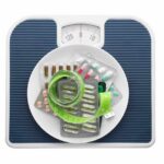 Alarm: Weight-Loss Shot Backfires? A scale topped with various medication packets and a measuring tape