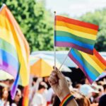 Person holding rainbow flags at a Pride event