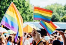 Person holding rainbow flags at a Pride event
