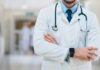 A doctor in a white coat with a stethoscope standing with arms crossed