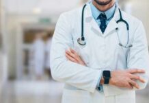 A doctor in a white coat with a stethoscope standing with arms crossed