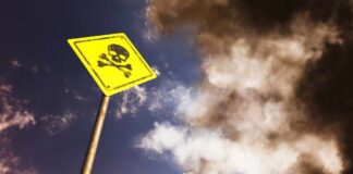 A yellow warning sign with a skull and crossbones against a cloudy sky