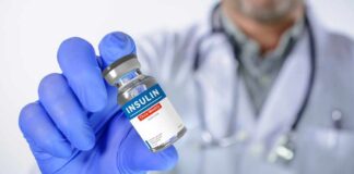 A healthcare professional holding an insulin vial in a gloved hand