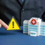 $3.5 BILLION Hospice Heist EXPOSED A business professional holding a warning sign next to a model of a hospital