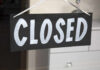 A black sign with the word 'CLOSED' painted in white letters