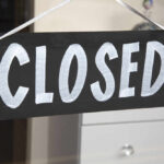 A black sign with the word 'CLOSED' painted in white letters