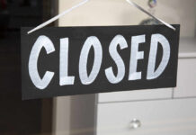 A black sign with the word 'CLOSED' painted in white letters