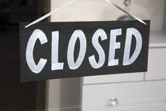 A black sign with the word 'CLOSED' painted in white letters