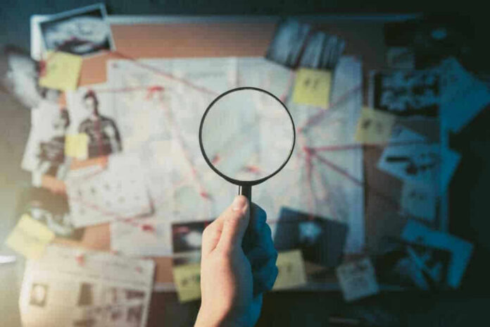 shutterstock_1192132651-1.jpg Magnifying glass over investigation board with photos and strings.