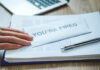 8,000 Jobs Slashed: AI Gold Rush Fallout A hand resting on an envelope labeled 'YOU'RE FIRED' on a desk with papers and a pen