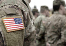 Shock Pentagon Move: Troops Cut Where? U.S. soldiers in camouflage uniforms with American flag patch.