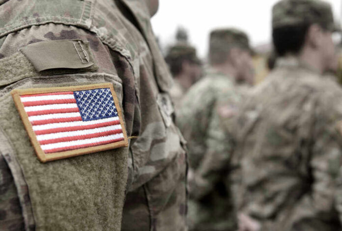 shutterstock_18369768851 U.S. soldiers in camouflage uniforms with American flag patch.