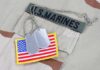 Close-up of military dog tags and an American flag patch on a US Marines uniform