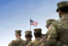 Army Drops Required Courses — Standards At Risk? Soldiers in uniform with American flag in background.