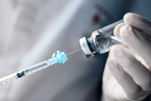 A healthcare professional preparing a syringe from a vial