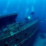 Divers exploring a sunken shipwreck underwater