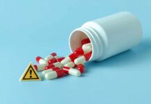 Spilled red and white capsules next to a warning sign