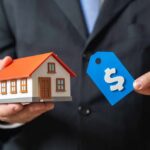 FORECLOSURE TSUNAMI Hits 119,000 Homeowners A person in a suit holding a miniature house and a price tag
