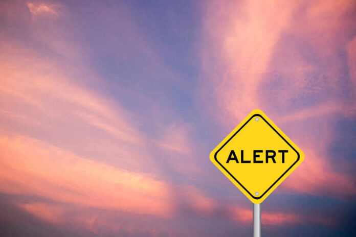 Yellow alert sign against a colorful sunset sky