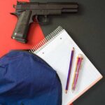 VIDEO: 3 Dead As Teen Gunfire Shocks Classroom Handgun beside school supplies and a blue backpack