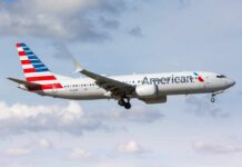 NOW: Fuel Shock Axes Airline Routes American Airlines airplane approaching for landing against a cloudy sky