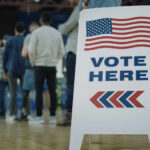 Trump Ally Surges — Enemies On Notice People in line next to Vote Here sign