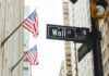 Wall Street Smacks Fox’s $22B Gamble Wall Street sign and traffic light in a city street with American flags
