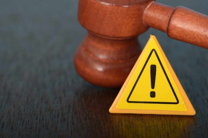 Judge's gavel beside yellow warning triangle sign