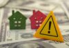 Colorful house models and a warning sign on dollar bills