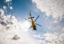 VIDEO: Deadly Crash In the Sky — What Went Wrong? A yellow helicopter flying against a backdrop of clouds and sunlight