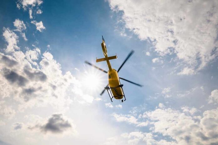Flying,Helicopter,Of,Emergency,Medical,Service,On,Sky,On,Sunny A yellow helicopter flying against a backdrop of clouds and sunlight