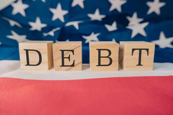Wooden,Block,With,The,Word,Debt,Written,On,It.,The Wooden blocks spelling 'DEBT' on a background of the American flag