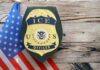 ICE Power Vacuum Ends? ICE officer badge displayed next to the U.S. flag