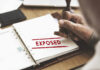 A hand stamping the word 'EXPOSED' on a document