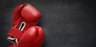 Red boxing gloves on a dark, textured surface.
